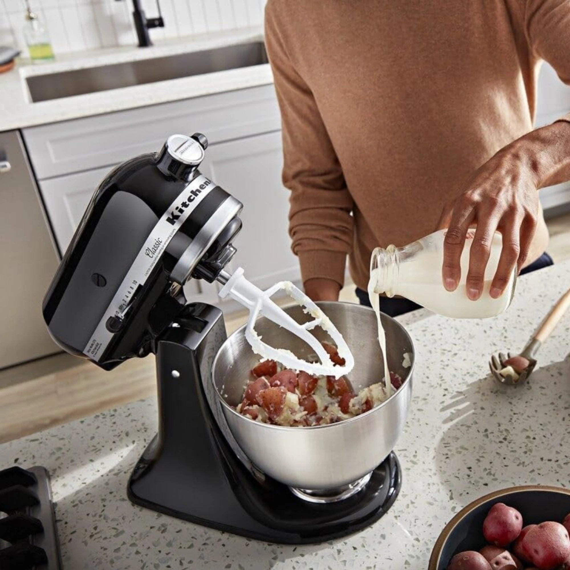 Batidora Planetaria Artisan KitchenAid negra con una persona usandola