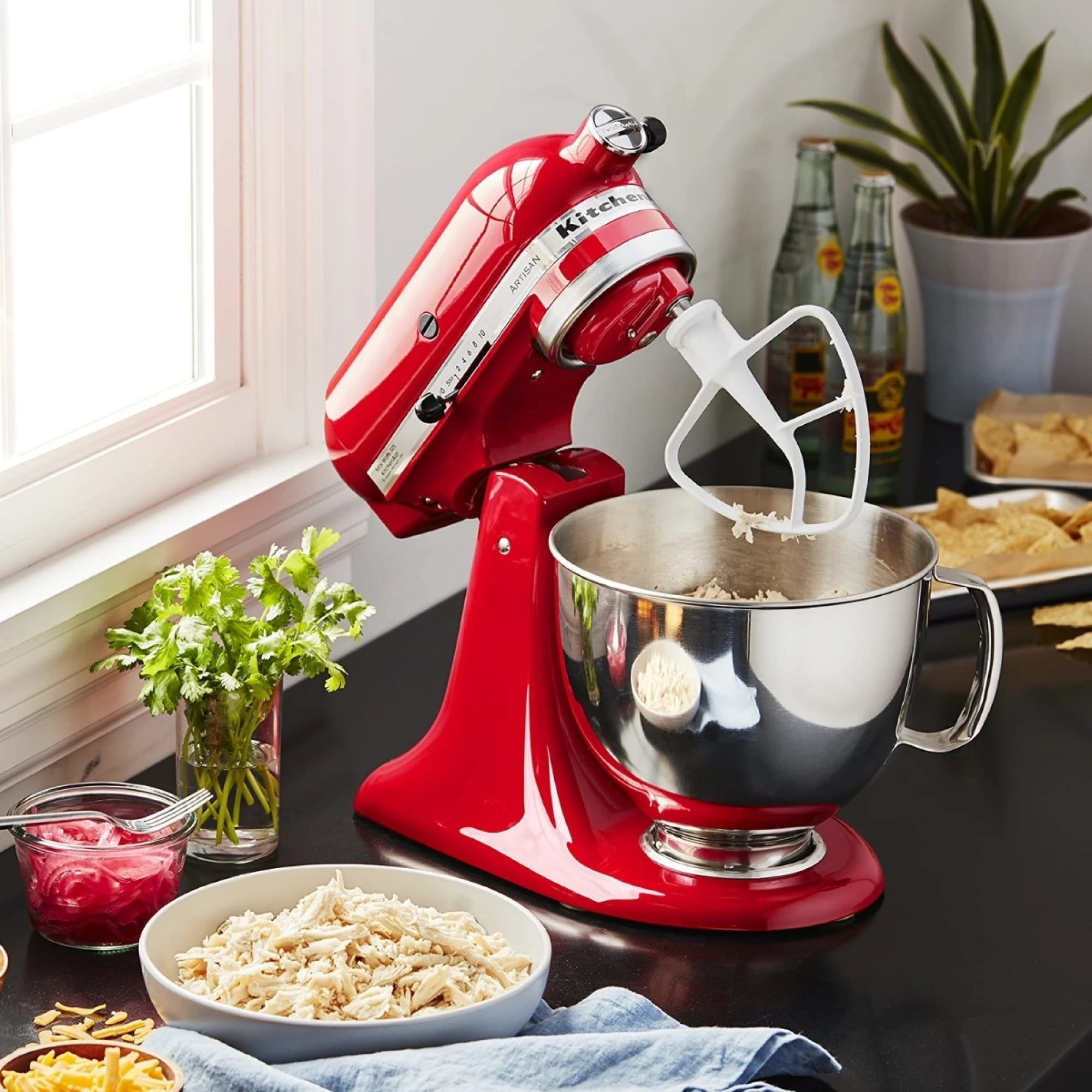 Batidora Planetaria Artisan KitchenAid roja funcionando en una mesada